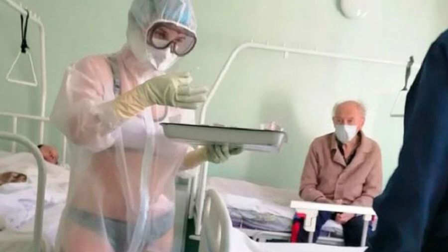 Sofocada por el calor, joven enfermera atiende en ropa interior a pacientes de COVID-19